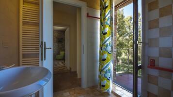 Un bagno con una vasca, un box doccia e vista su un balcone con ringhiera.