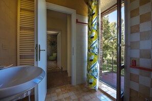 Ein Badezimmer mit Badewanne, Duschvorhang und Blick auf einen Balkon mit Geländer.