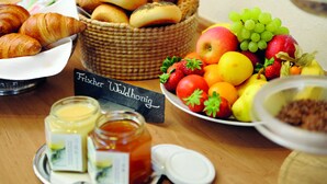 A breakfast buffet with bread, fruits, and condiments. - Hotel Gräffs-Mühle (Traben-Trarbach)
