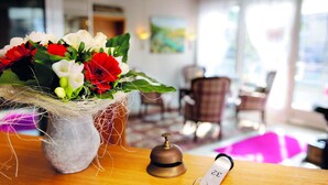 A wooden reception desk with a vase of flowers, a bell, and a keychain. - Hotel Gräffs-Mühle (Traben-Trarbach)