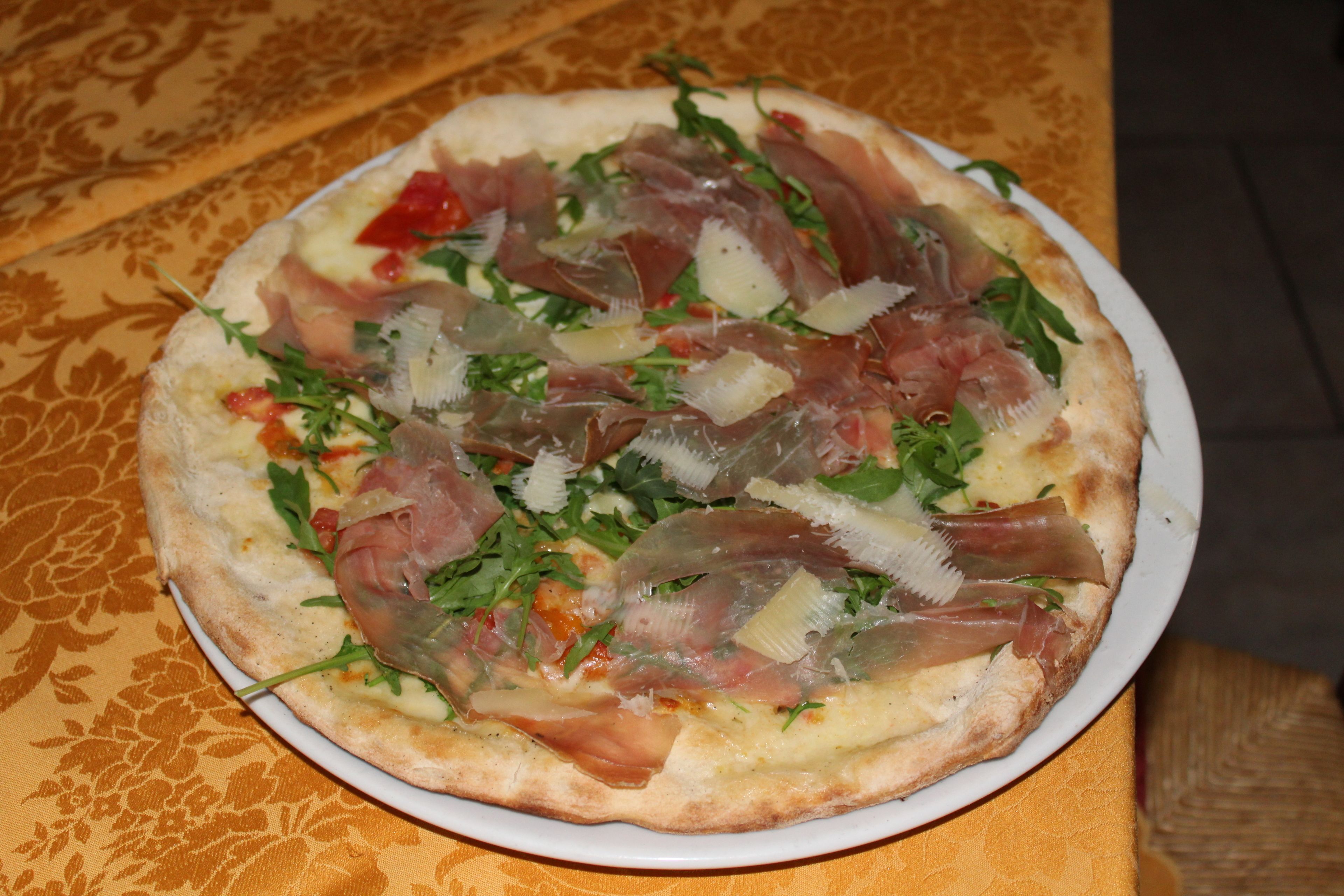 Una pizza con diversos ingredientes servida en un plato blanco.