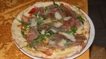 Una pizza con diversos ingredientes servida en un plato blanco.