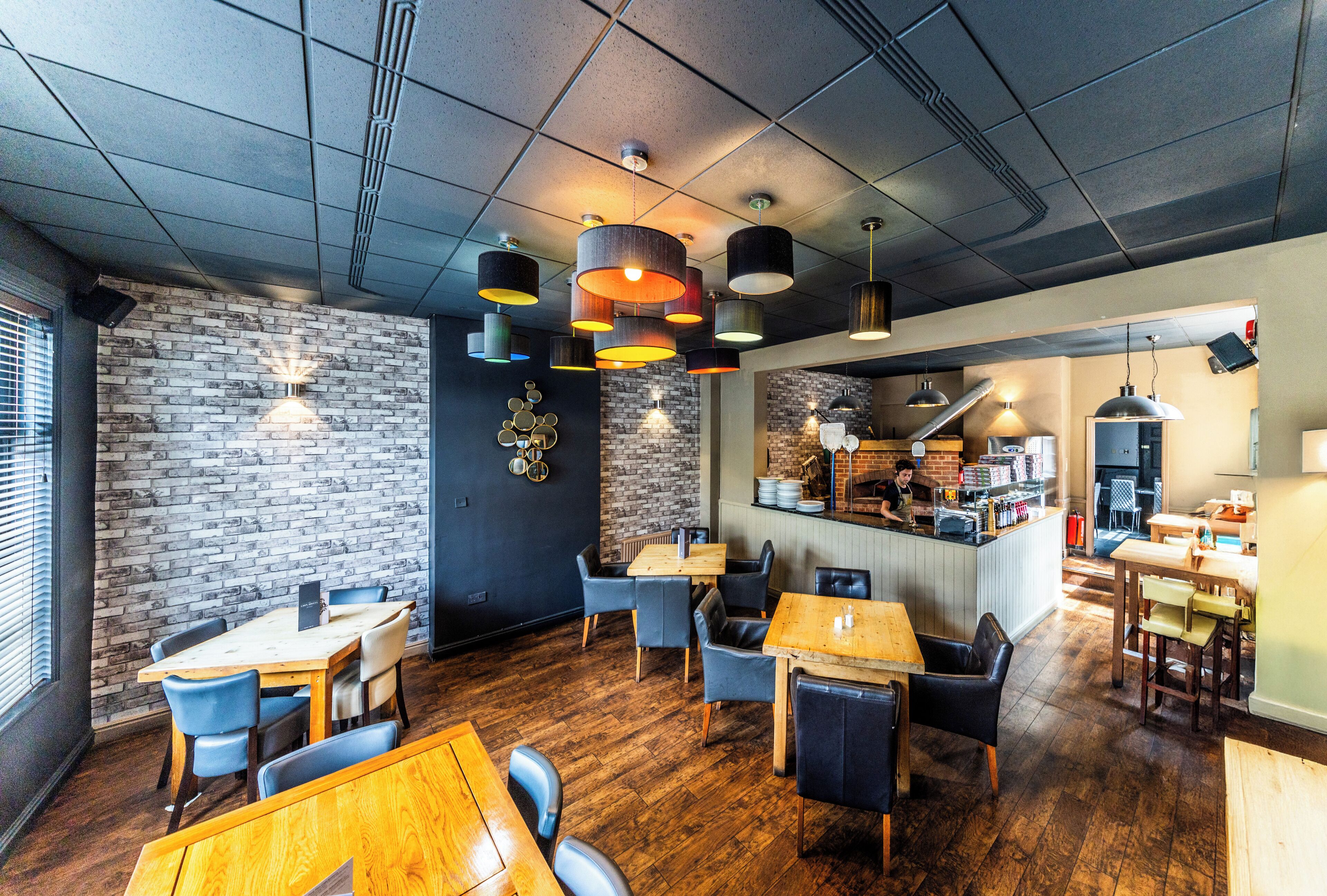 A restaurant interior with brick walls, wooden tables, and modern pendant lighting.