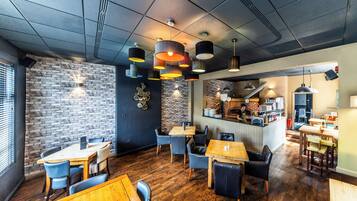A restaurant interior with brick walls, wooden tables, and modern pendant lighting.