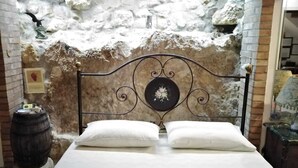 A bed with a metal headboard in a room with a stone wall. - La Corte Normanna (Sciacca)