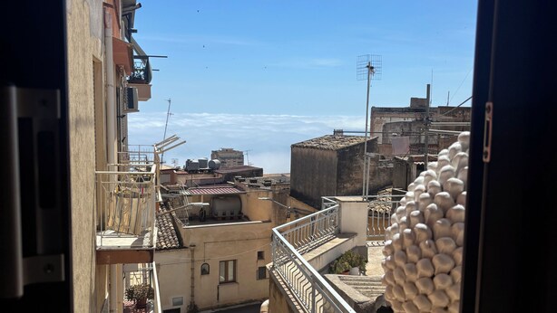 A view from a window overlooking a cityscape with buildings, a clear sky, and a tiled floor. - La Corte Normanna (Sciacca)