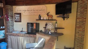 A bar area with a rustic design, a television mounted on the wall, and a decorative sign with a quote. - La Corte Normanna (Sciacca)