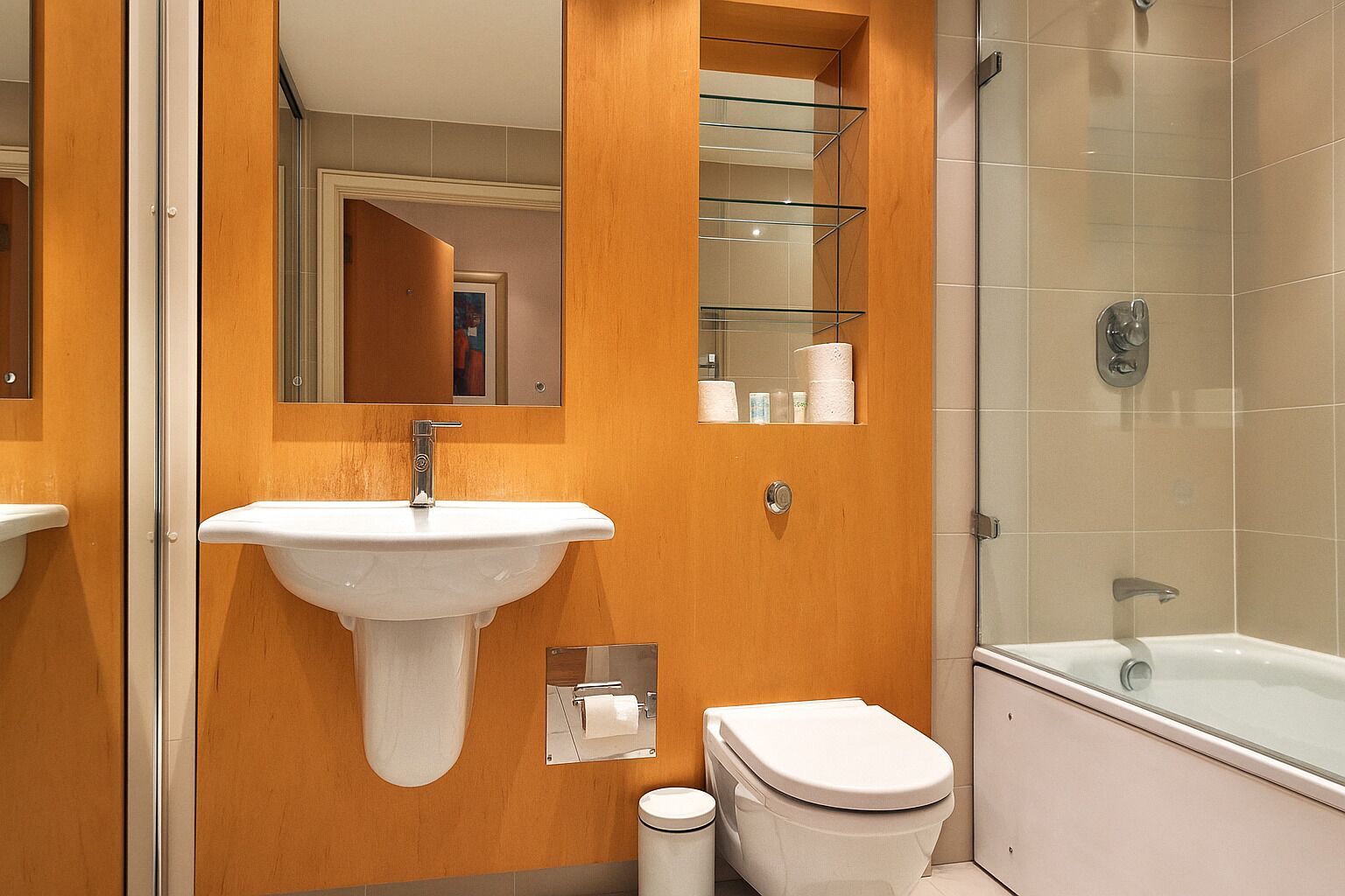 Une salle de bain avec un lavabo blanc, des toilettes et une douche à parois de verre.