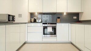 A modern kitchen with white cabinets, a built-in oven, a microwave, and a toaster.