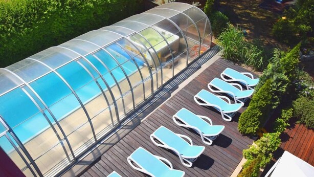 Una piscina techada con sillones de descanso y un jacuzzi.