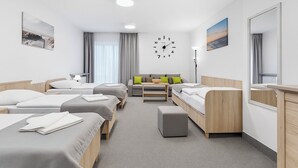 Habitación de hotel con dos camas individuales, un sofá, una mesita y un espejo.