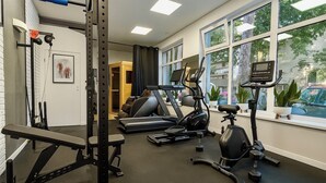 Un gimnasio en casa con barra de dominadas, banco de pesas, elíptica y bicicleta estática.