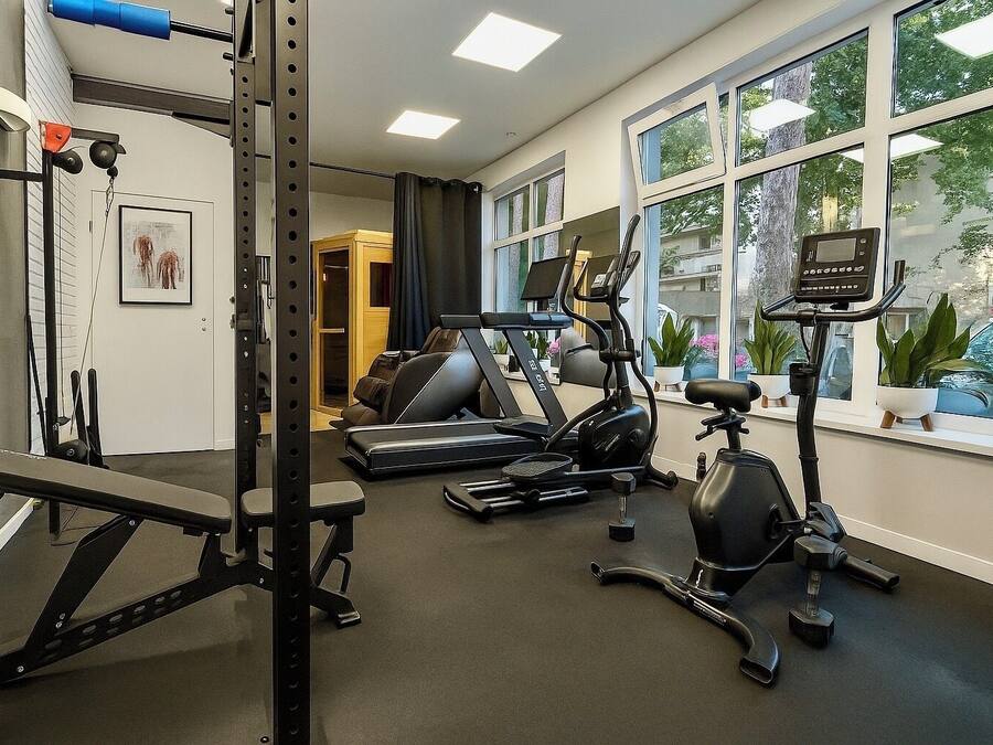 Un gimnasio en casa con barra de dominadas, banco de pesas, elíptica y bicicleta estática.