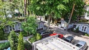Maqueta de una zona residencial con casas, coches y un espacio de estar cubierto al aire libre.