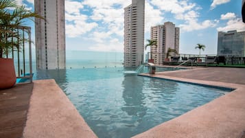 Enjoy breathtaking ocean views from our rooftop pool, surrounded by comfortable lounge chairs and lush greenery.