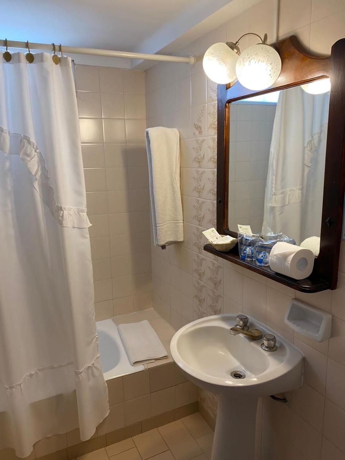 A bathroom with a shower curtain, a sink, a mirror, and a towel rack.