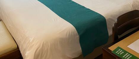 Una habitación de hotel con una pared revestida de madera, una cama grande con ropa de cama blanca y aguamarina, y un cuadro sobre la cama.