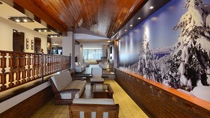 Un vestíbulo de hotel con techo de madera, pared de ladrillo con un mural y un área de descanso con sofás y sillones.