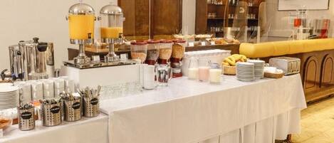 Un buffet proposant une variété de plats et de boissons, notamment un coin café avec des distributeurs et un bar à jus.