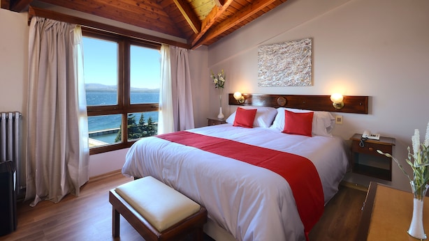 Un dormitorio con una cama grande, cabecera de madera, mesita de noche y vista al mar.