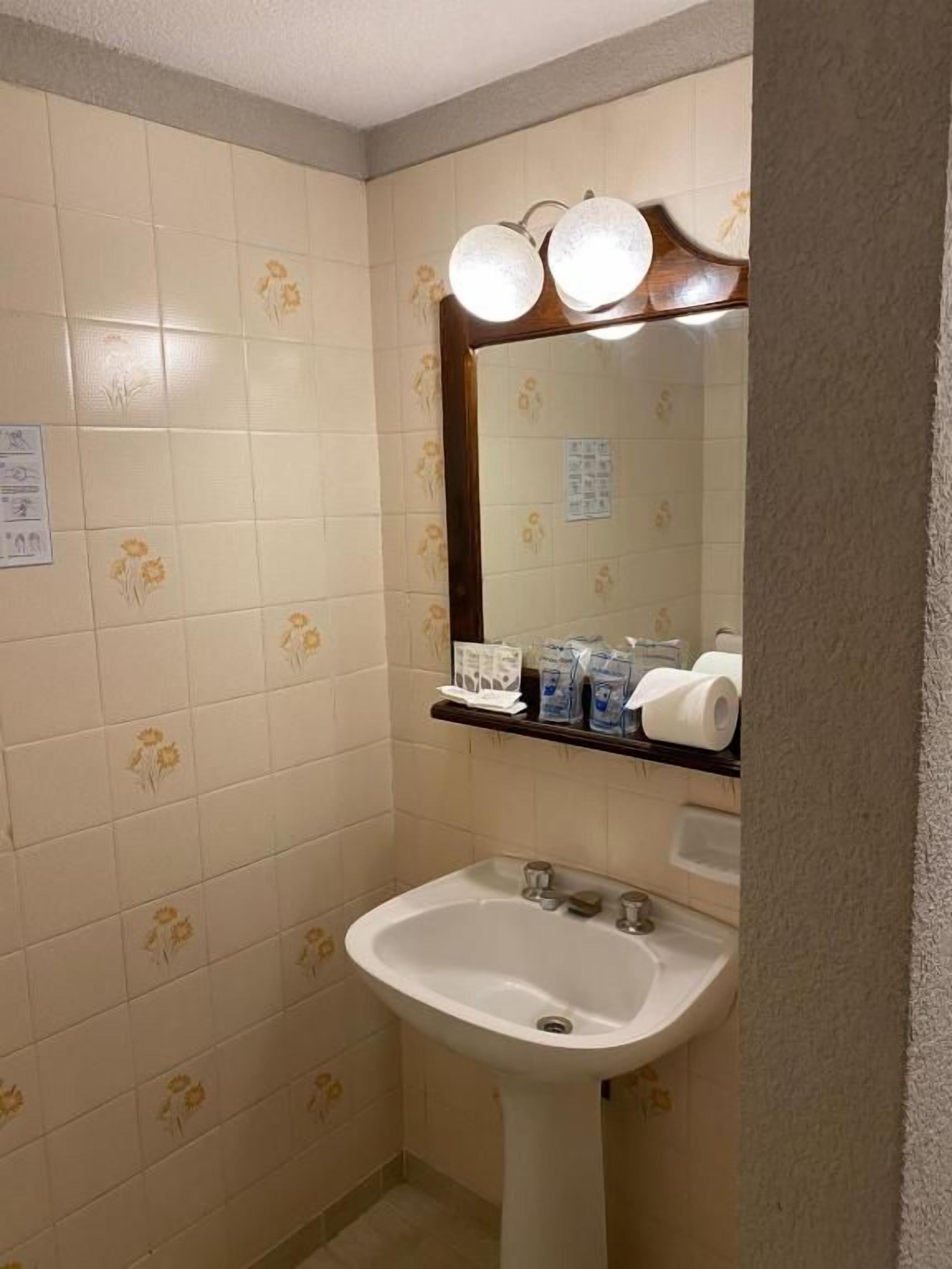 Ein Badezimmer mit Waschbecken, Spiegel und Beleuchtung.