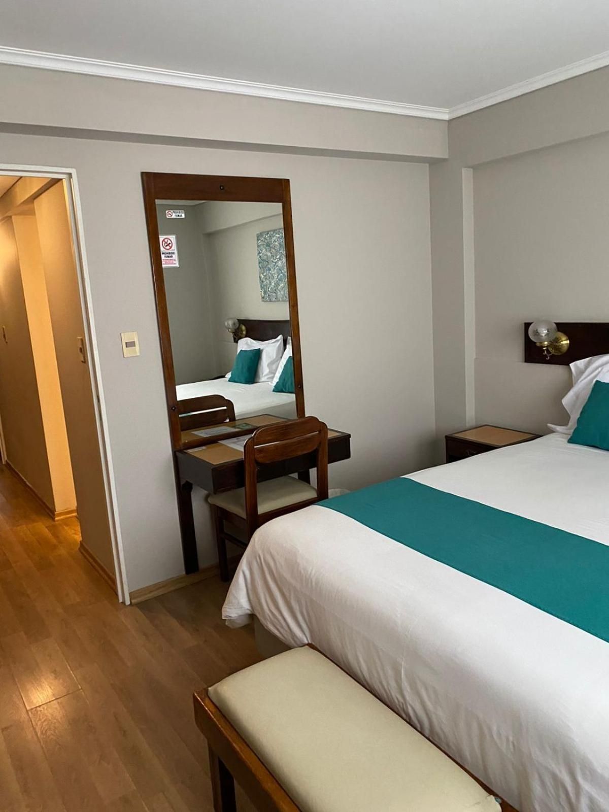 Ein Hotelzimmer mit Bett, Schreibtisch, Stuhl, Nachttisch und Spiegel.