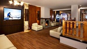 Una sala moderna con una pared de piedra, suelo de madera, chimenea y televisor montado en la pared.