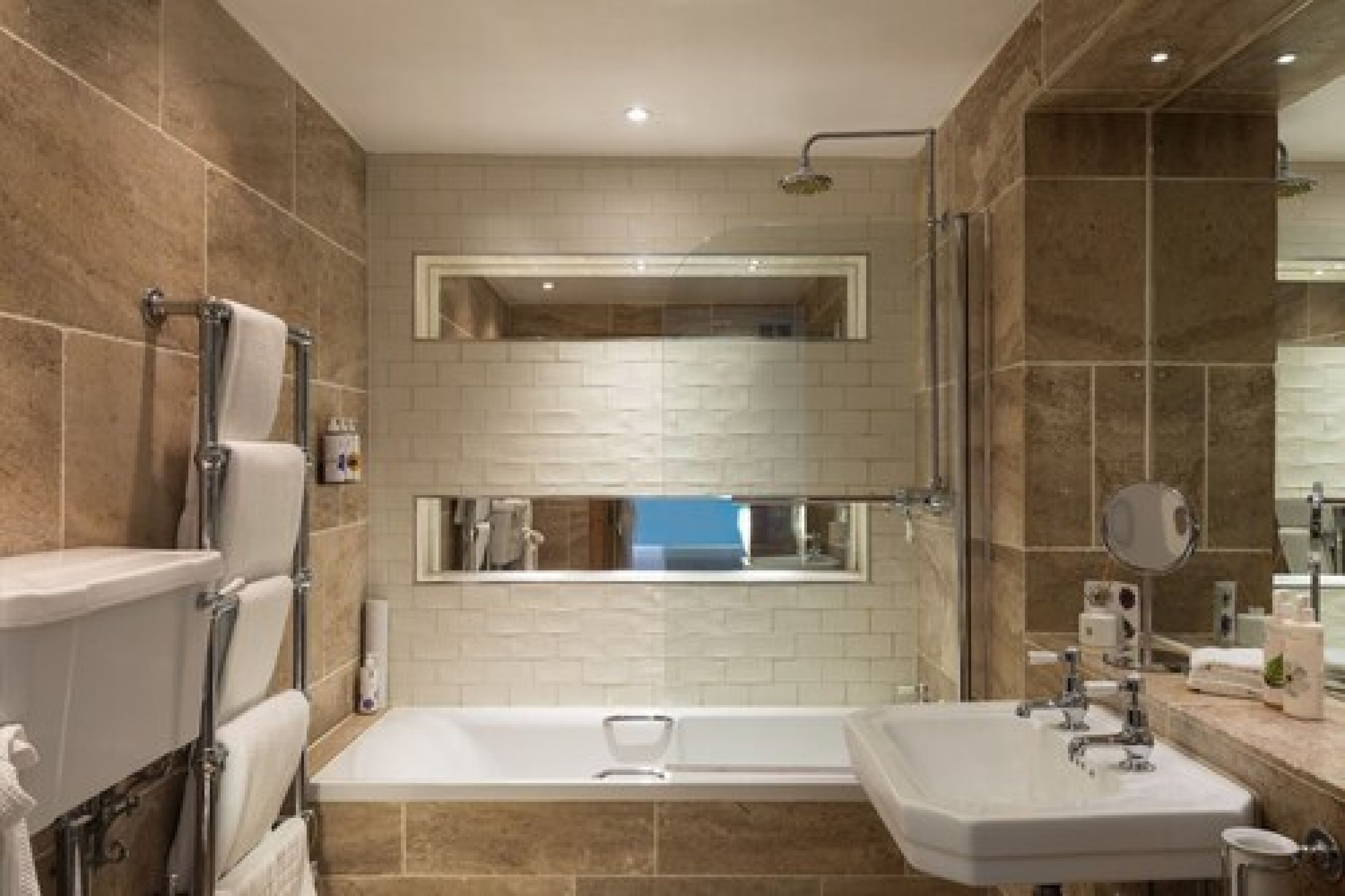 A modern bathroom with a double sink, a bathtub, and a large mirror above the sink.