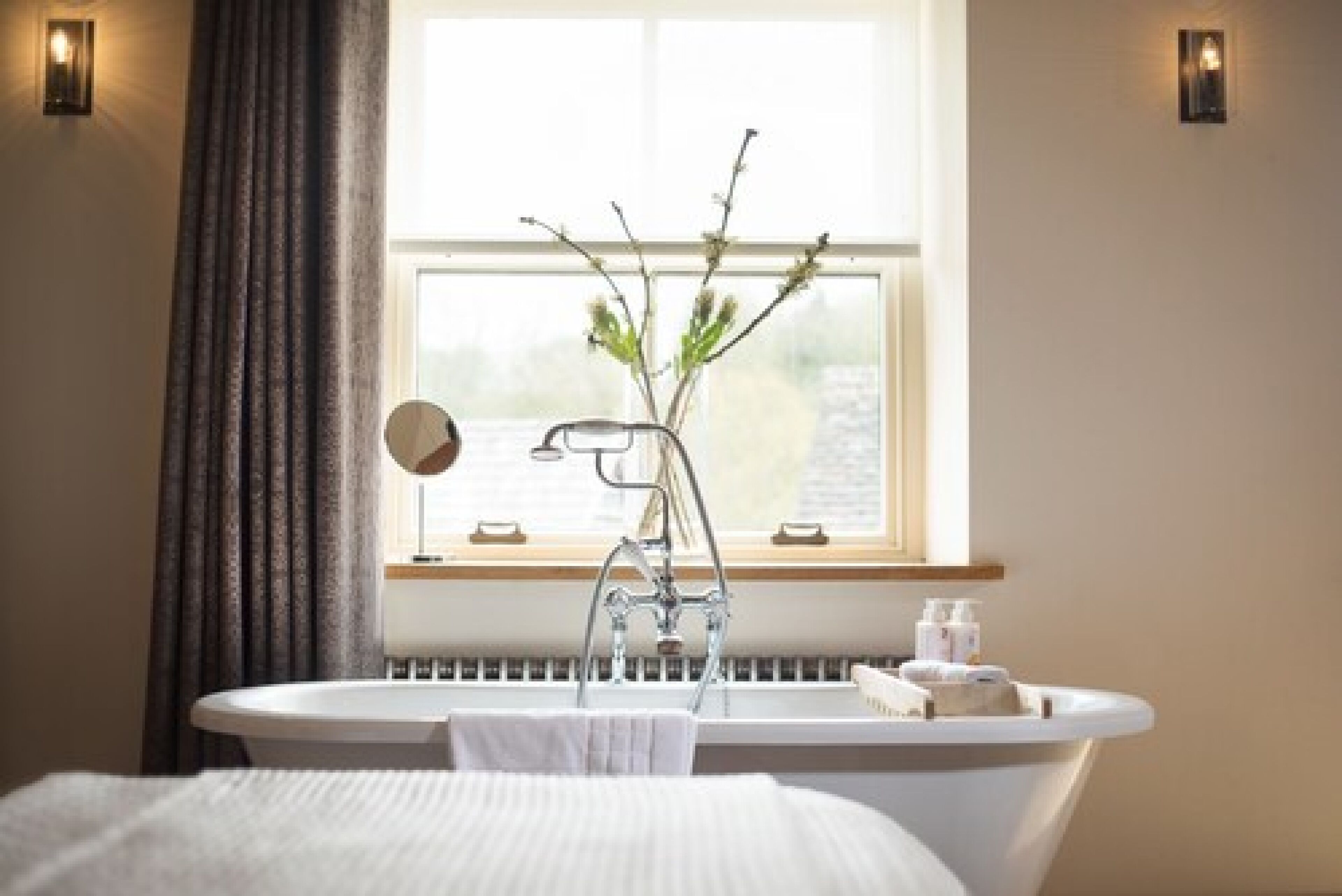 A bathroom with a bathtub, a mirror, a window with a view, and a radiator.