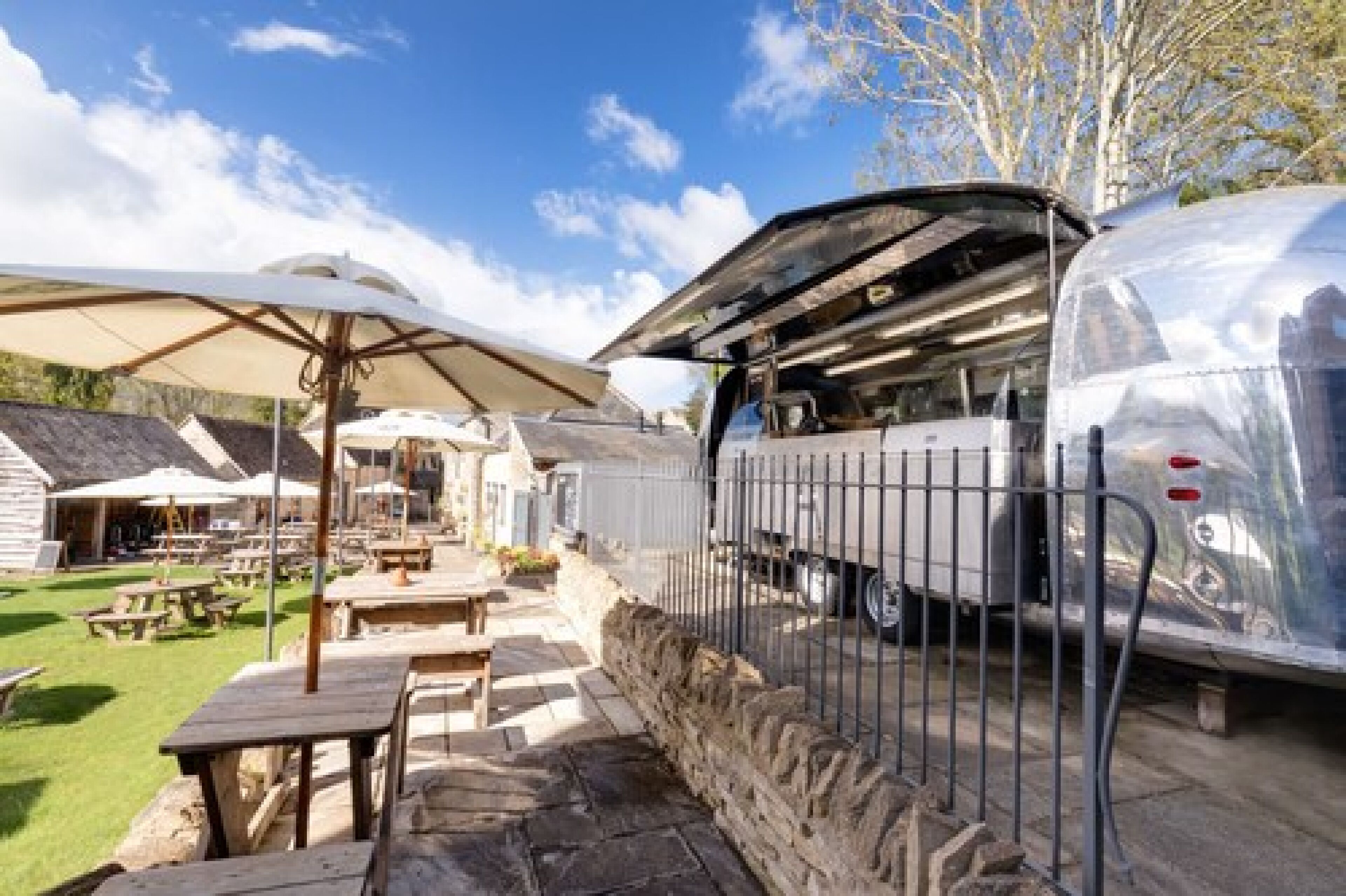 A mobile home with a covered patio area, outdoor tables, and a grill.
