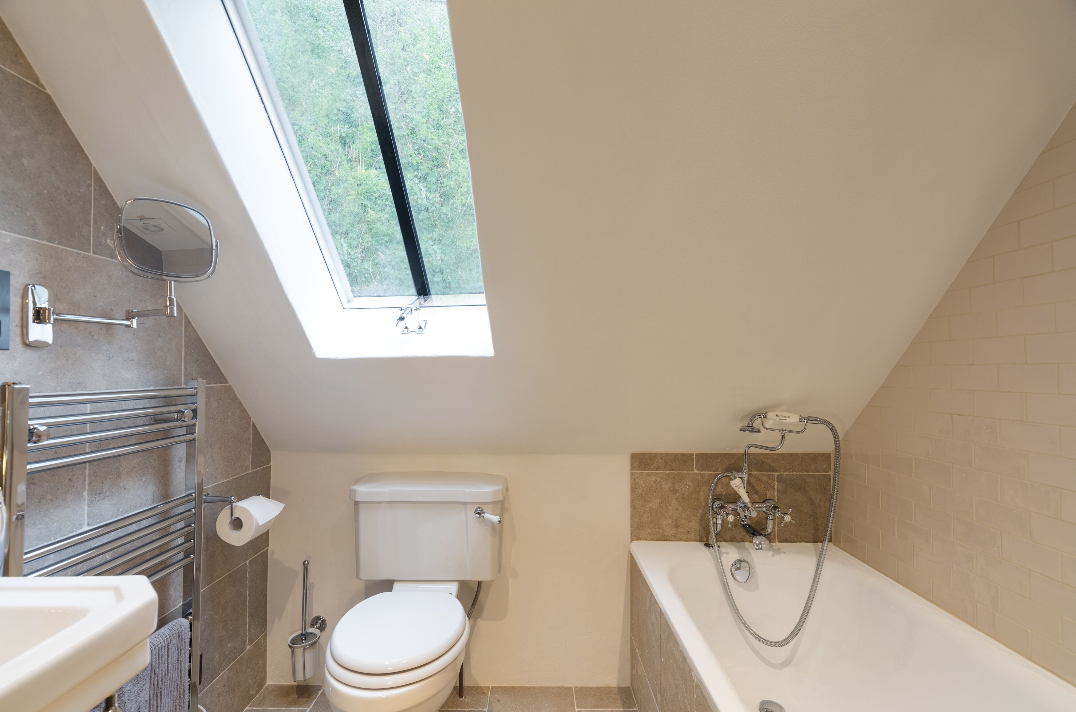 A modern bathroom with a skylight, a toilet, a bathtub, and a towel rack.