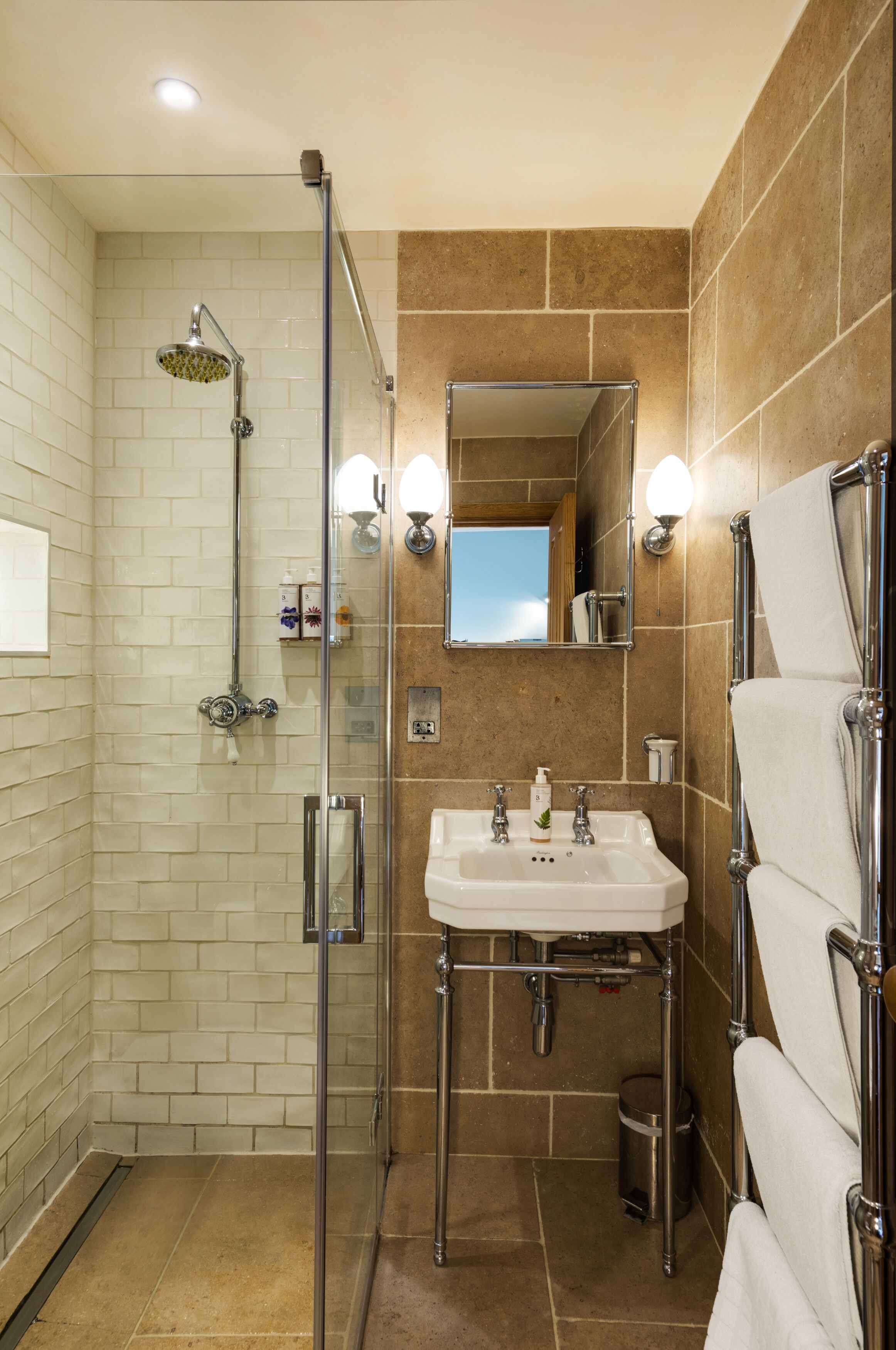 Un baño moderno con ducha de vidrio, lavamanos con espejo y toallero.