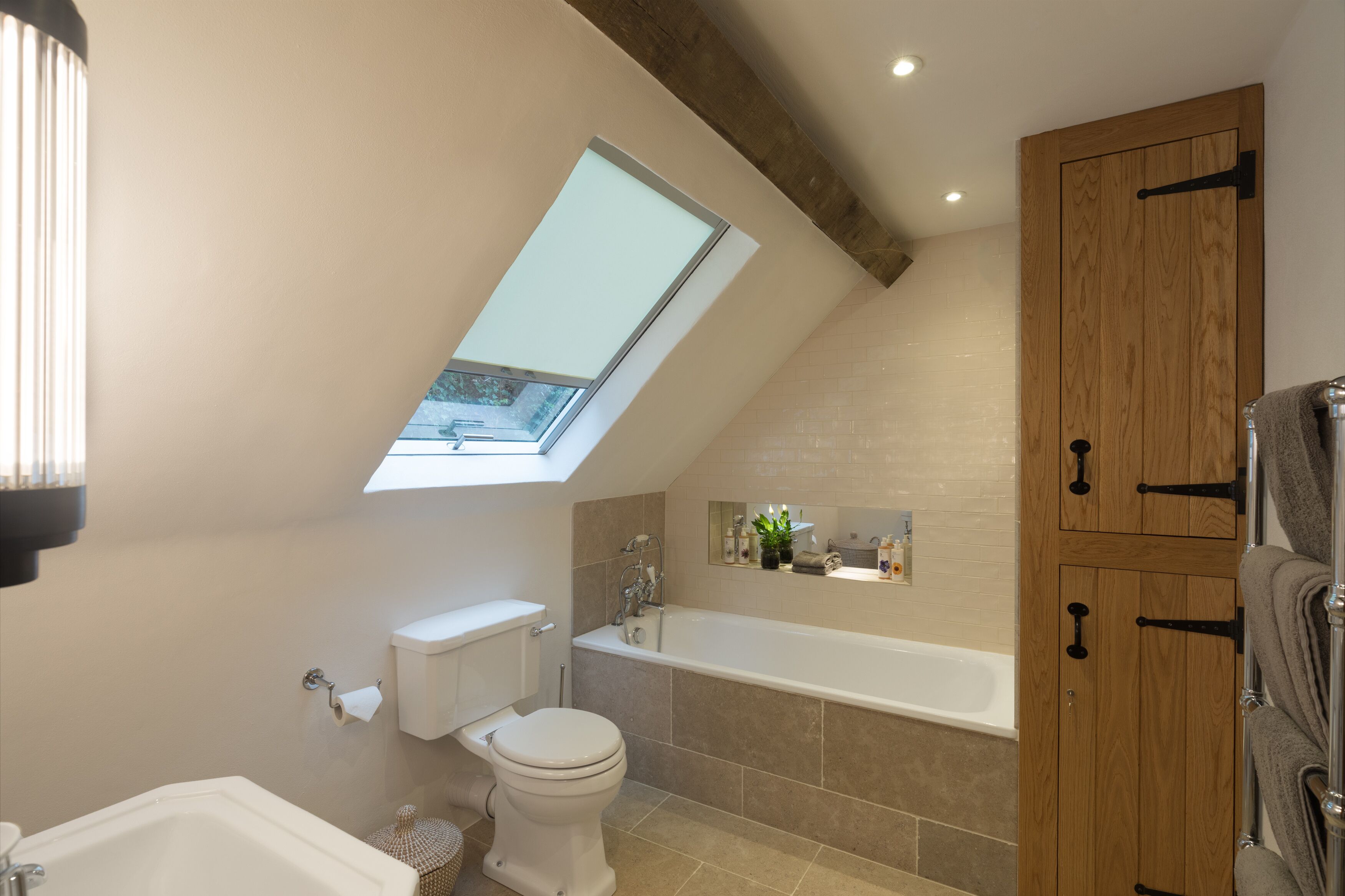 A modern bathroom with a skylight, a bathtub, and wooden cabinets.