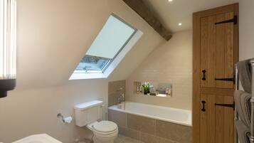 A modern bathroom with a skylight, a bathtub, and wooden cabinets.