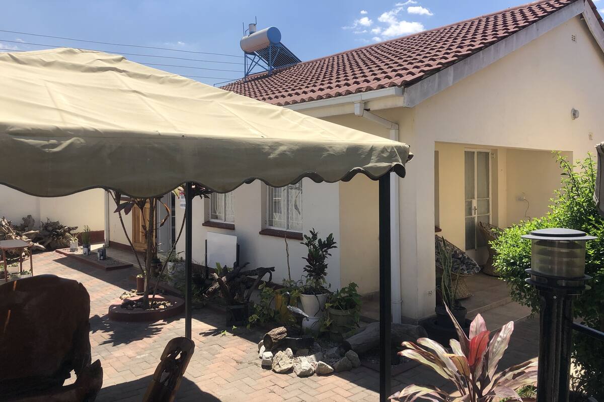 A house with a tiled roof, a covered patio area, and various potted plants.