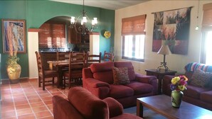 A living room with a red sofa, a wooden dining table, and a kitchen in the background. - FN460- Charming Cozy Luxury Villa (Loreto)