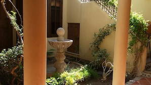 A courtyard with a stone fountain, a wooden door, and climbing plants. - FN460- Charming Cozy Luxury Villa (Loreto)