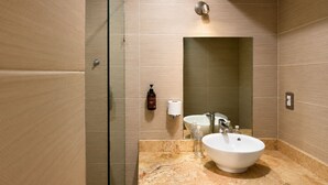 Un baño moderno con cabina de ducha de vidrio, lavamanos de mármol y un espejo grande.