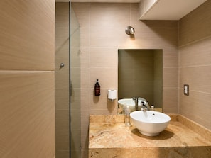 A modern bathroom with a glass shower enclosure, a marble sink, and a large mirror.