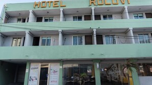 Un hotel llamado "HOTEL ROLOVI" con fachada verde, varios balcones y un letrero que anuncia el restaurante "Star Juice".