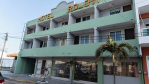 Un hotel de varios pisos con fachada verde y balcones.