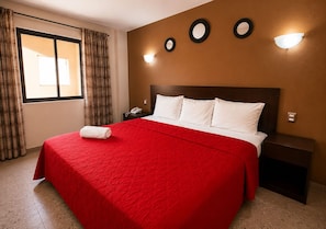 A hotel room with a large bed, a nightstand, a telephone, and a window with curtains. - Hotel Rolovi (Veracruz)