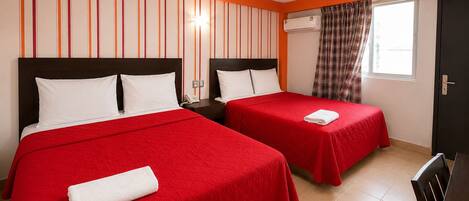 A hotel room with two beds, a window with curtains, an air conditioning unit, and a wall with vertical stripes.