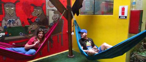 A room with a colorful mural, a hammock, and a fire extinguisher on the wall.
