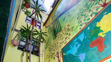 A vibrant indoor garden with a mural, a small waterfall, and various plants.