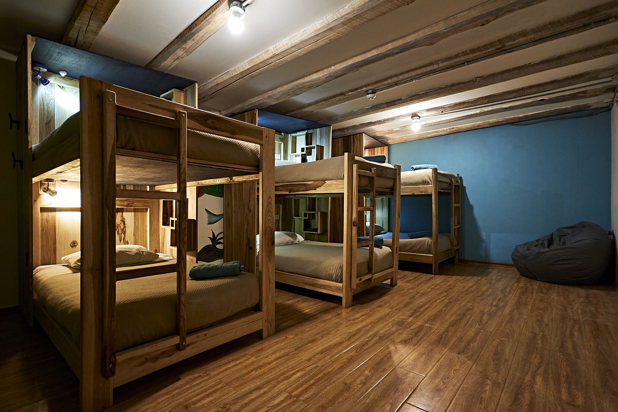 Une chambre avec des lits superposés, un plancher en bois et un fauteuil en forme de poire.