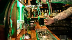Un bar avec un robinet, des bouteilles et une main tenant un verre.