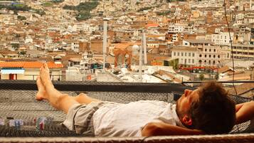Una persona recostada en una hamaca con vista a un paisaje urbano denso y arquitectura histórica.
