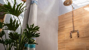 Un espace douche doté d’un sol en bois, d’une plante en pot et d’un pommeau de douche.
