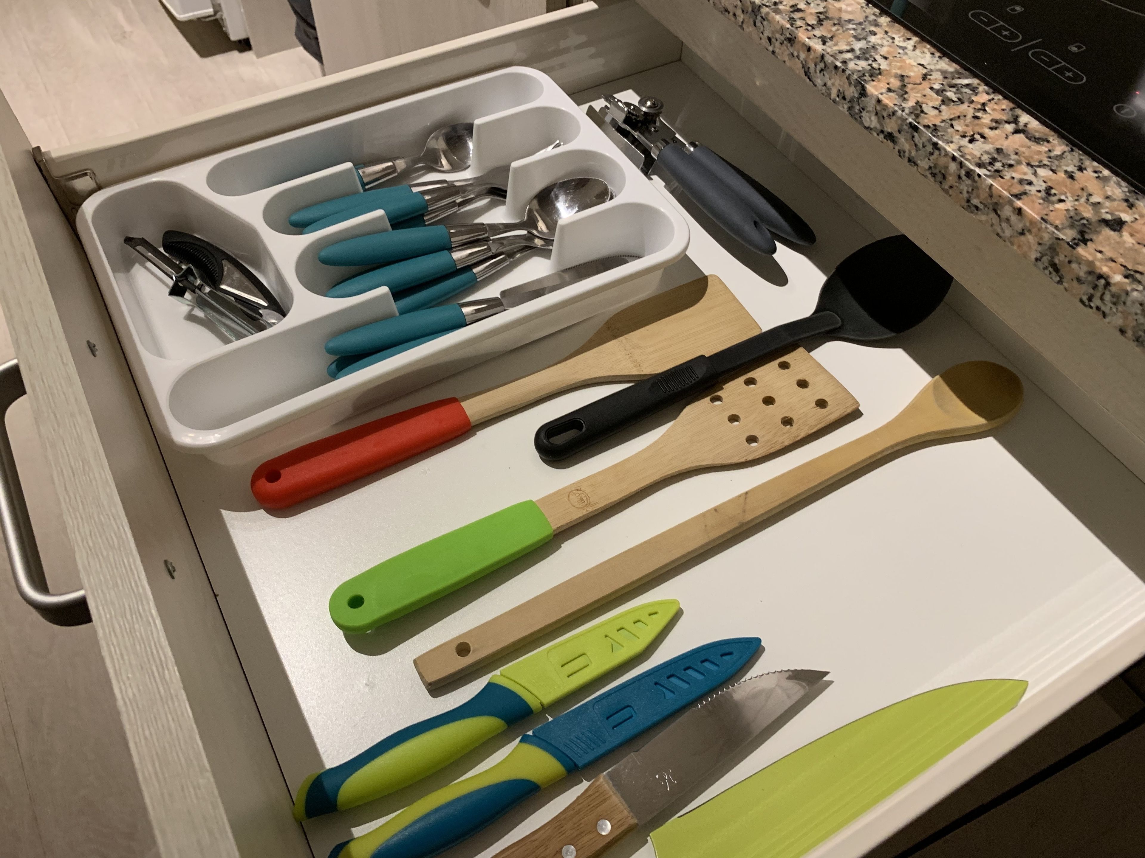 A drawer with various kitchen utensils including spoons, spatulas, and knives.